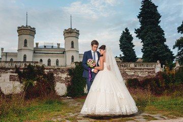 Stylish bride stands with groom before an old house