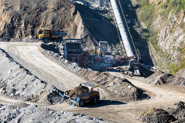 Open-pit mine with dump trucks.Heavy mining dump trucks driving along the opencast.Quarry ore.