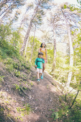 A woman and her child walk along a forest trail.