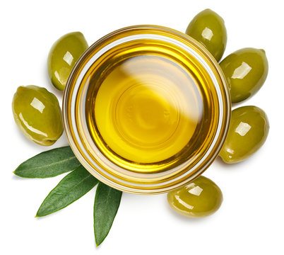 Bowl of olive oil and green olives with leaves