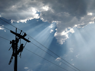 Power lineman maintain high-strength distribution system. The backdrop is a beautiful blue sky.