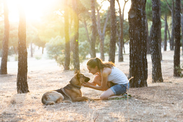 Young attractive latin woman teaching and loving her beautiful cute german shepherd dog in the park at sunset in nature care support happiness peaceful friendship training animals lifestyle concept.