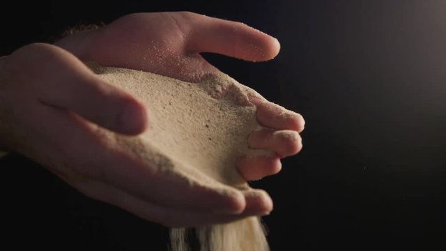 Two hands trying to hold on to sand.