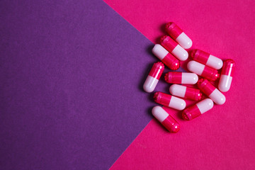 Assortment of various colourful pills on pastel coloured background.