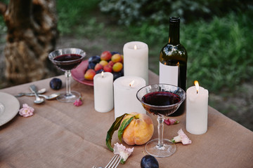 candles and red wine on table in garden