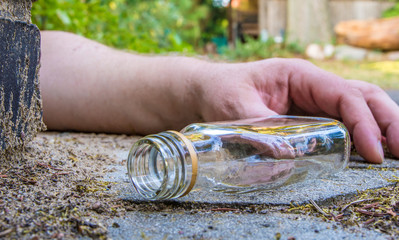 ein betrunkener Mann und eine leere Schnapsflasche liegen auf der Strasse
