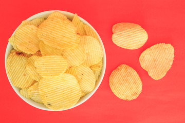 crispy potato chips junk food unhealthy food on bowl red background