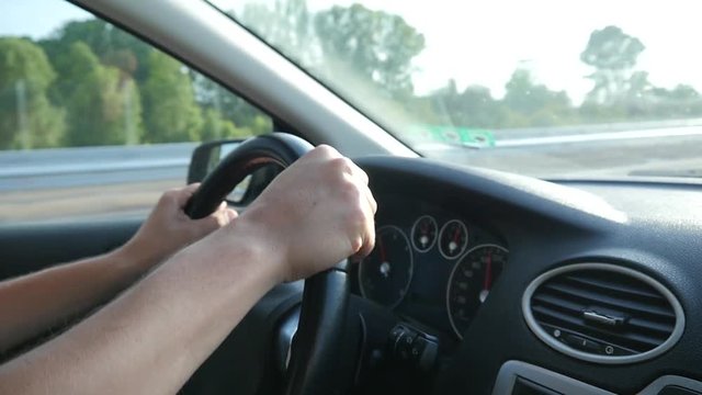 Man drives the car holding hands on the steering wheel on autobahn highway