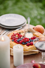 pie with berries, candles on table in garden