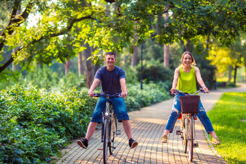 Obraz premium Happy family. Happy father and mother with kid on bicycles having fun in park..