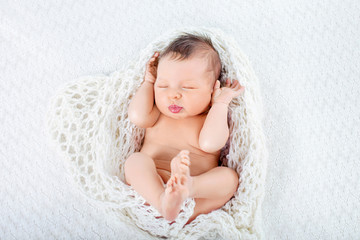 Sleeping newborn baby boy lies  in a knite plaid