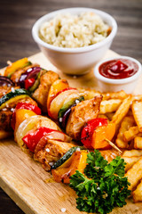 Kebabs - grilled meat with french fries and vegetables on wooden background 