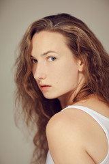 Naklejka premium Beautiful young woman with long curly hair and natural make up beauty portrait, looking into camera