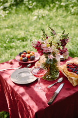 wineglass and bouquet of flowers on table in garden