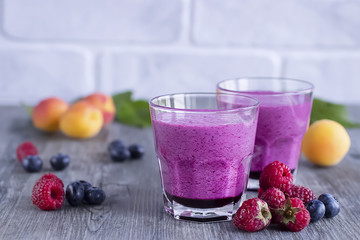 Smoothies of fresh berries and fruits in  glasses on  gray wooden table.