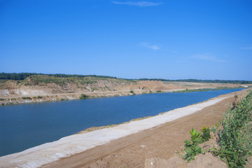Sand pit filled with water. A developed, flooded quarry. On the shore are white and yellow sand.