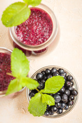 Blueberry smoothie close up photography - top view of summer blended vitamin cocktail decorated with mint leaves.
