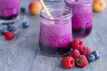 Smoothies of fresh berries and fruits in  glasses on  gray wooden table.
