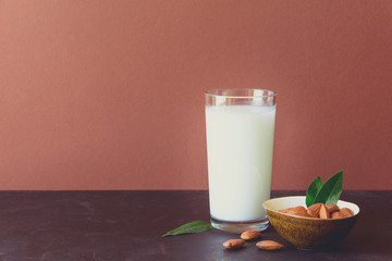 Almond milk with almond on a brown wooden table. Healthy eating concept. Toned