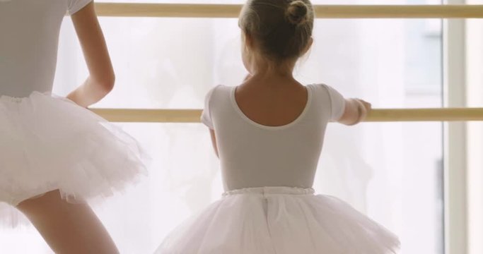 A teacher of classical dance teaches some steps to his young student who wants to learn how to dance and in the background the other little girls who listen. Concept of: ambition, education, teaching