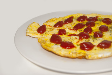 Fried eggs with greens, decorated with drops of ketchup, on a white plate