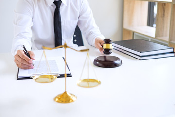 Businessman or lawyer working on a documents, judge gavel with Justice lawyers at law firm in background, Legal law, advice and justice concept