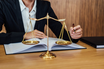 Gavel on wooden table and female Lawyer or Judge working with agreement in Courtroom theme, Justice and Law concept