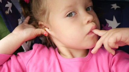 Little girl child sucks a finger - she put into a mouth her dirty hands