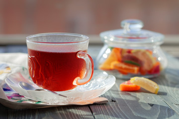 Close up of a morning black tea and colorful marmalades in glass jar on wooden table.