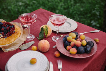 glasses of wine, berries pie and fruits on table in garden