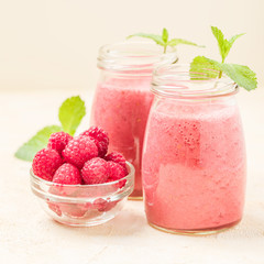 Raspberry smoothie close up photography with fresh summer blended cocktail and ripe berries on pastel yellow background.