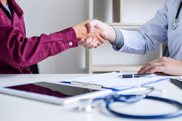 Professional Male doctor in white coat shaking hand with female patient after successful recommend treatment methods, Medicine and health care concept