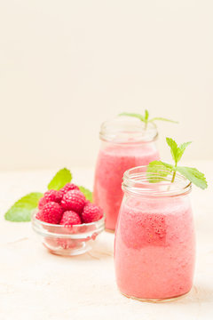 Raspberry smoothie close up photography with fresh summer blended cocktail and ripe berries on pastel yellow background.