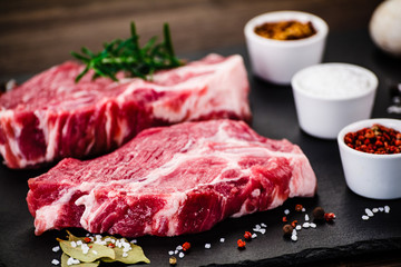Raw pork on black stone on wooden background