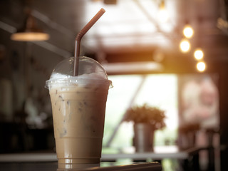 Glass of iced coffee with milk on blurred background.