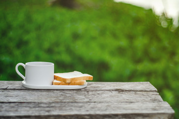 Breakfast set on wooden floor in the morning. Breakfast with coffee and bread.Do not focus on objects.