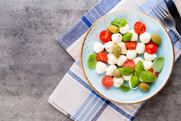 Delicious caprese salad with ripe cherry tomatoes and mini mozzarella cheese balls with fresh basil leaves.