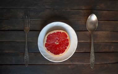 pink grapefruit on a white plate and Cutlery
