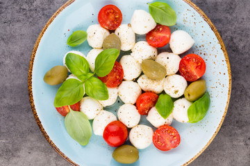Delicious caprese salad with ripe cherry tomatoes and mini mozzarella cheese balls with fresh basil leaves.
