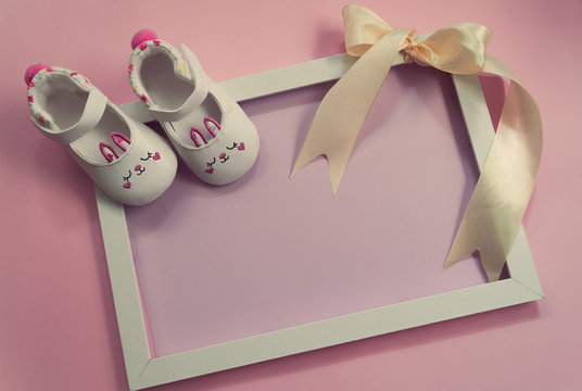 Childrens shoes for girls, stands on a pink background. on frame with ribbon. Closeup view from the top. the concept of children's clothing. Copyspace included.