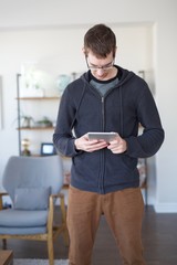 Young hip man using iPad in living room