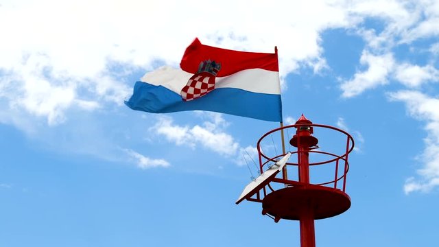 Lighthouse, light beacon pole with flying Croatian flag in daylight, slow motion 4x, close up shot, light beacon powered with solar cells