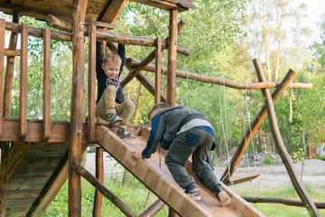 A little boy is climbing a children's hill in the park in the summer. The child is 3-5 years old. Active rest on a children's playground.