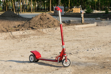 Children's red scooter on the road in the park.