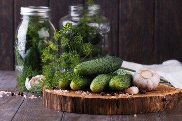 Preserved cucumbers in glass jars with garlic and dill on table