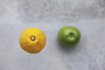 Lemon and green apple on grey background. Top view
