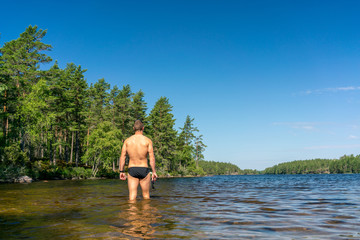 Fit man goes into a swedish lake to swim