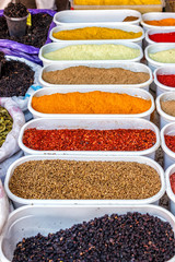 Many multicolored spices in the vessels on the table.