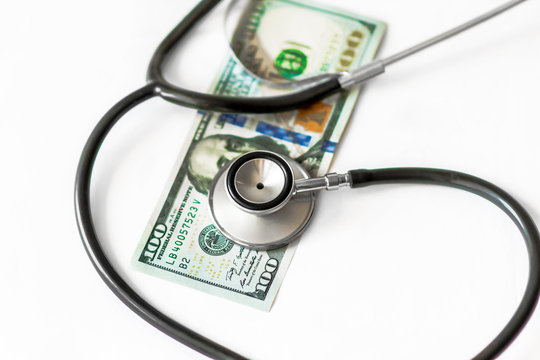 Medical stethoscope on hundred dollar banknote money on white background. Concept of health care costs, finance, health insurance funds, cost rising