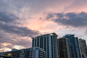 Fototapeta na wymiar Sunny Isles Beach, USA dramatic cloudscape skyline looking up perspective of apartment hotel buildings during colorful sunset evening in Miami, Florida with skyscrapers urban exterior skyscape